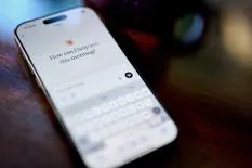 Close-up of a smartphone displaying a virtual assistant's greeting, 'How can I help you this morning?' with a keyboard interface.
