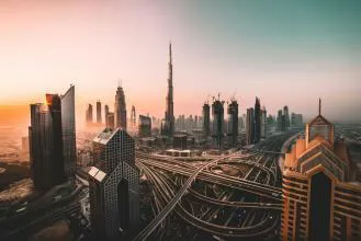 A breathtaking view of Dubai's skyline during sunset, featuring iconic skyscrapers including the Burj Khalifa, with busy roadways and construction in the foreground.