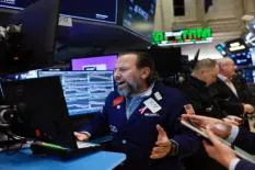 A Wall Street trader passionately reacting while working at his computer during trading hours.